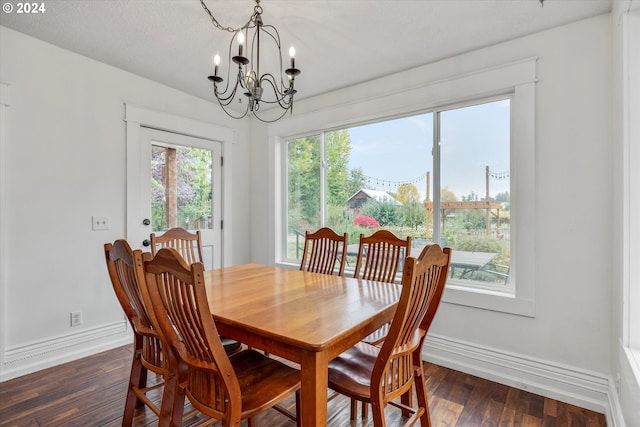 dining room featuring dark wood-type flooring, a notable chandelier, a textured ceiling, and a wealth of natural light