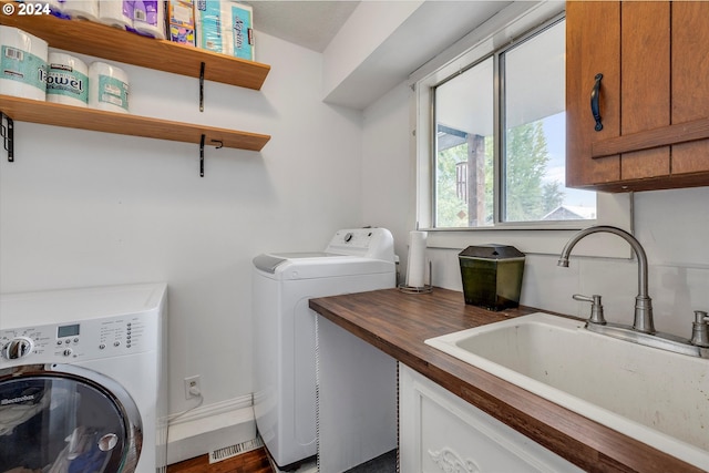 laundry room featuring separate washer and dryer, cabinet space, and a sink