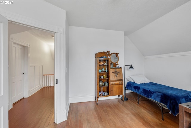 bedroom featuring hardwood / wood-style floors, baseboards, and lofted ceiling