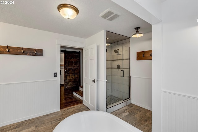 bathroom with hardwood / wood-style floors, plus walk in shower, and a textured ceiling