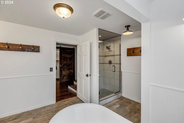 full bath featuring a shower stall, a wainscoted wall, wood finished floors, and visible vents