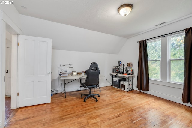 office space with lofted ceiling, visible vents, light wood finished floors, and baseboards