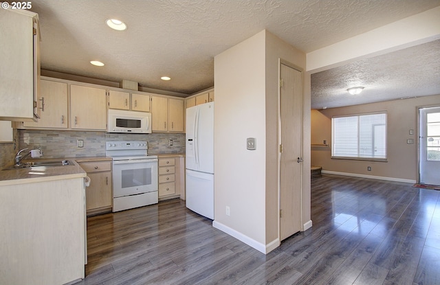 kitchen with white appliances, decorative backsplash, light countertops, light brown cabinetry, and a sink