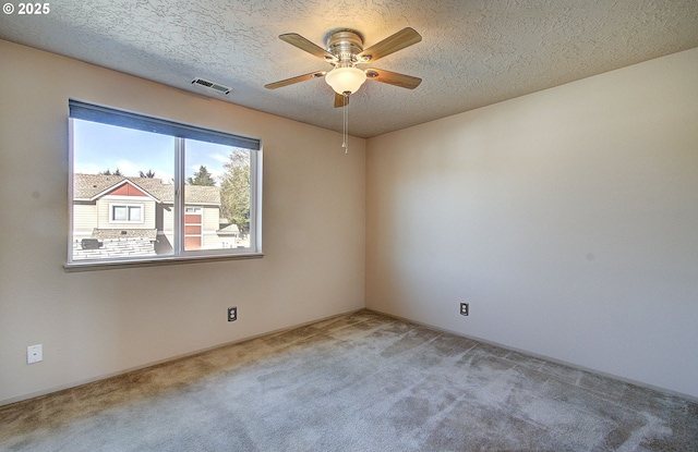 unfurnished room with a textured ceiling, a ceiling fan, visible vents, and light colored carpet