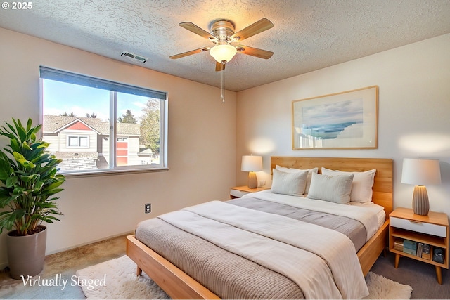 bedroom with visible vents, ceiling fan, a textured ceiling, and carpet flooring