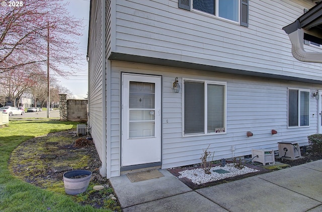 doorway to property with central AC and a lawn