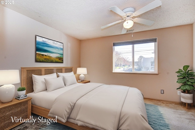 carpeted bedroom featuring a ceiling fan, visible vents, and a textured ceiling