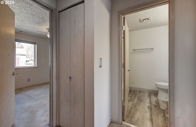 bathroom featuring a textured ceiling, toilet, wood finished floors, visible vents, and baseboards