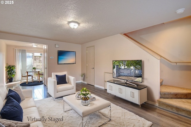 living room featuring baseboards, stairway, a textured ceiling, and wood finished floors