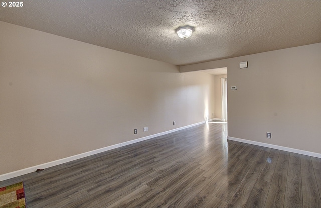 spare room featuring baseboards, dark wood finished floors, and a textured ceiling