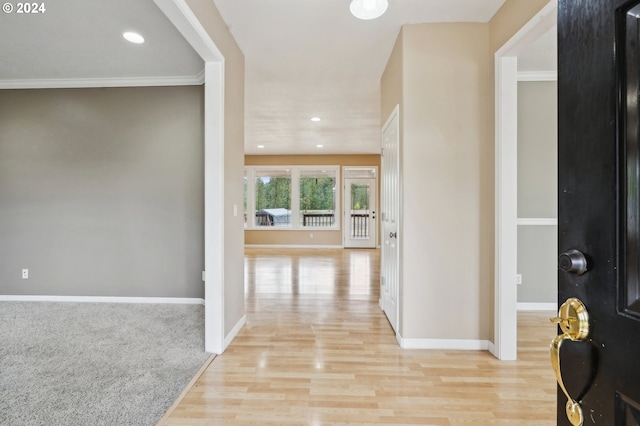 hallway with light hardwood / wood-style floors and ornamental molding