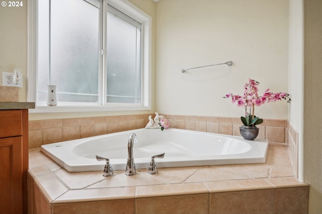 bathroom featuring vanity, a relaxing tiled tub, and plenty of natural light