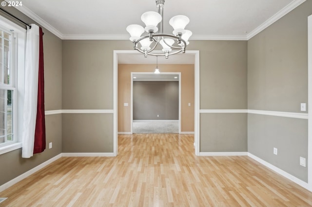 empty room with crown molding, an inviting chandelier, and light hardwood / wood-style flooring