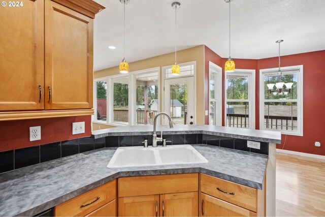 kitchen featuring decorative light fixtures, light hardwood / wood-style floors, sink, and a wealth of natural light