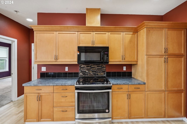 kitchen with light wood-type flooring, stainless steel range oven, and tasteful backsplash