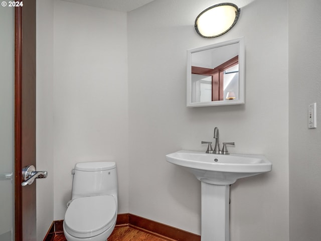 bathroom featuring wood-type flooring and toilet