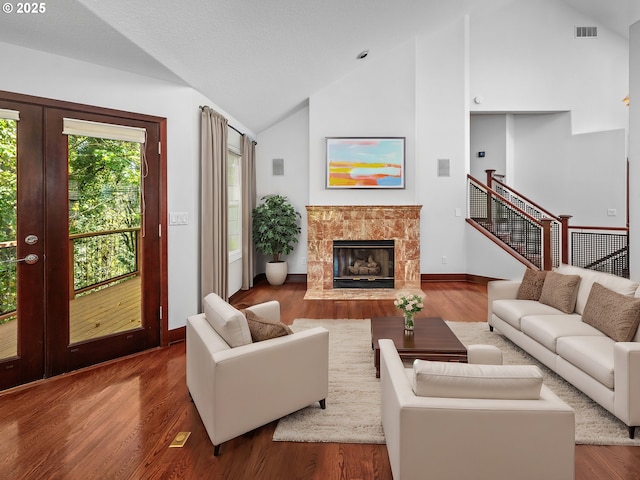 living room featuring hardwood / wood-style floors, high vaulted ceiling, a premium fireplace, and french doors