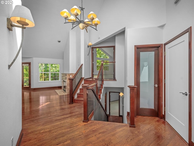 hallway with wood-type flooring, high vaulted ceiling, and a chandelier