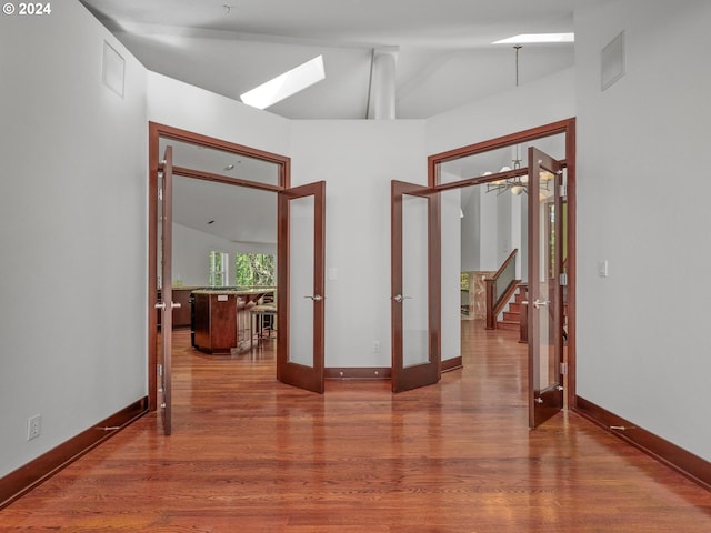 empty room with french doors, wood-type flooring, and vaulted ceiling