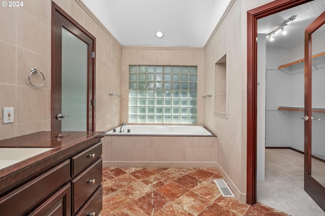 bathroom with crown molding, tile walls, a textured ceiling, and tiled tub