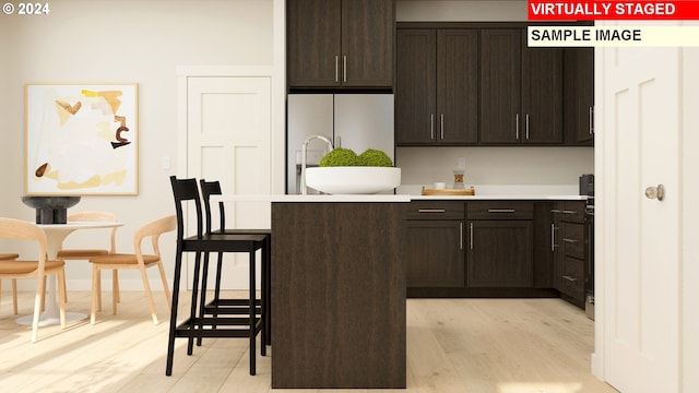 kitchen with dark brown cabinets, light wood-type flooring, and white refrigerator