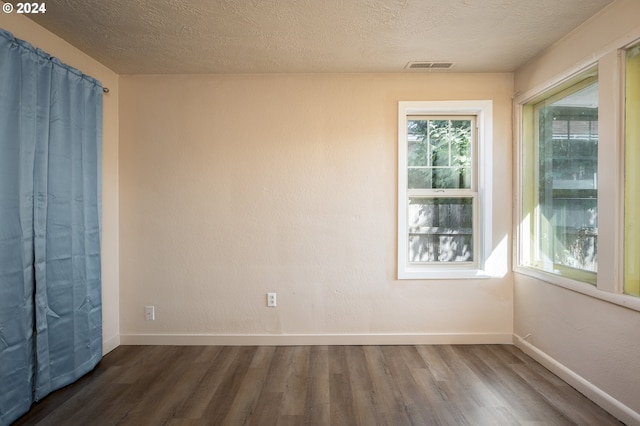 unfurnished room featuring a textured ceiling and dark hardwood / wood-style floors