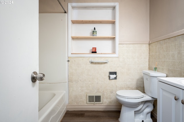 bathroom featuring vanity, toilet, hardwood / wood-style flooring, and tile walls