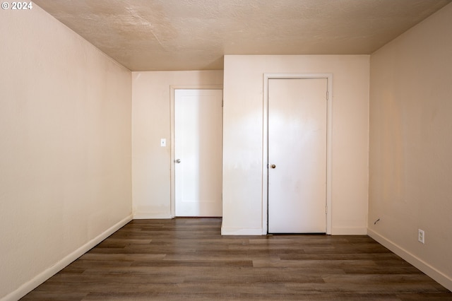 unfurnished bedroom featuring dark wood-type flooring, a textured ceiling, and a closet