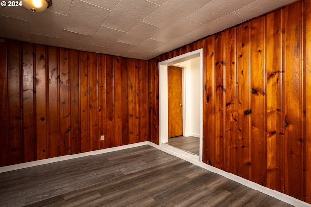 spare room with wood finished floors, baseboards, and wood walls