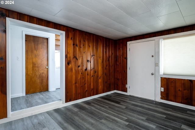 unfurnished room featuring dark wood-type flooring and wood walls