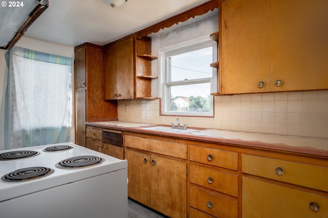 kitchen with a sink, tile counters, tasteful backsplash, and white range with electric stovetop