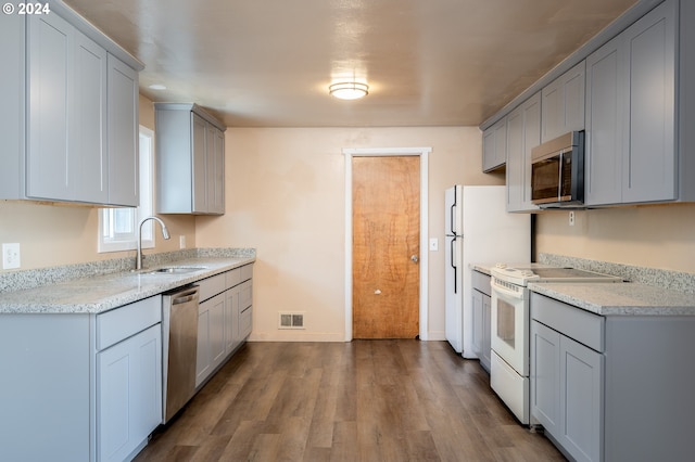 kitchen with dark wood-style floors, visible vents, gray cabinets, a sink, and stainless steel appliances