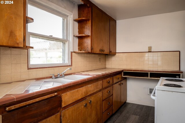 kitchen featuring dark hardwood / wood-style flooring, sink, electric stove, tile counters, and tasteful backsplash