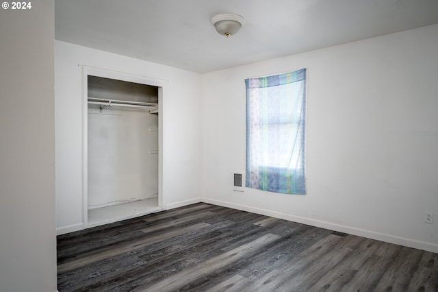 unfurnished bedroom featuring visible vents, baseboards, a closet, and dark wood finished floors