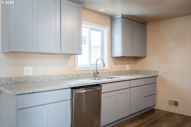 kitchen with gray cabinetry, dishwasher, dark wood-type flooring, sink, and light stone counters