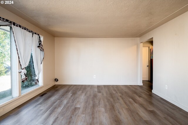 unfurnished room with a textured ceiling and wood-type flooring