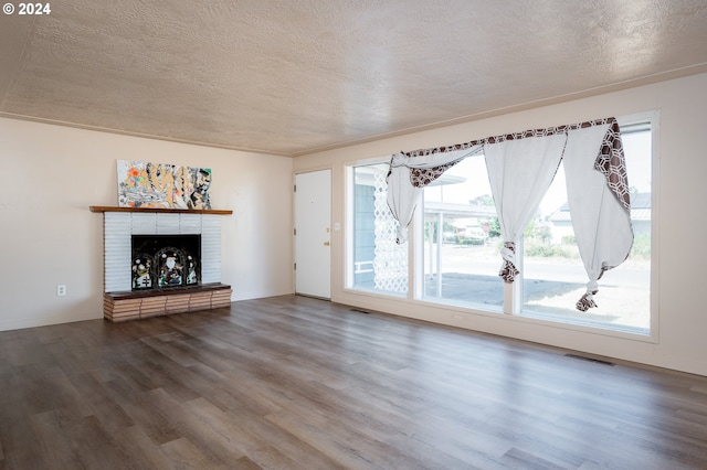 unfurnished living room with a textured ceiling, a brick fireplace, and hardwood / wood-style floors