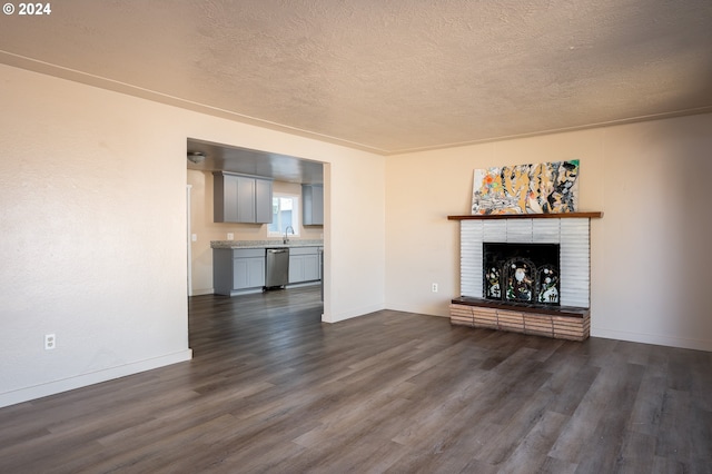 unfurnished living room with a sink, a textured ceiling, dark wood-style floors, baseboards, and a brick fireplace