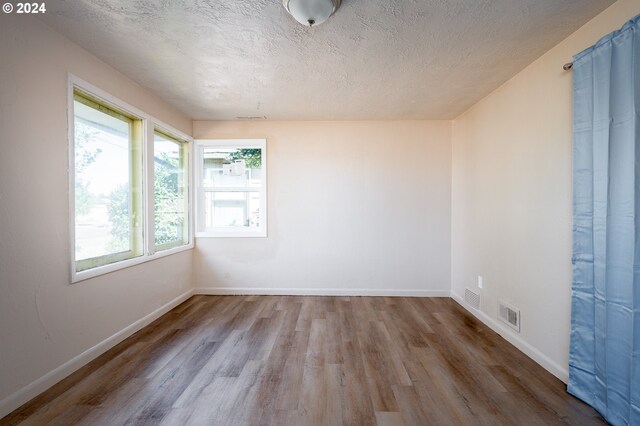 empty room featuring a textured ceiling and hardwood / wood-style floors