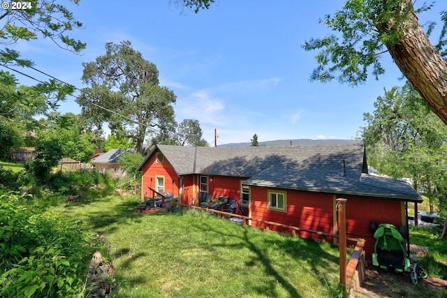 back of house featuring a yard and roof with shingles