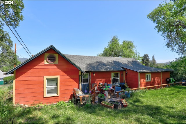 rear view of house featuring roof with shingles and a lawn