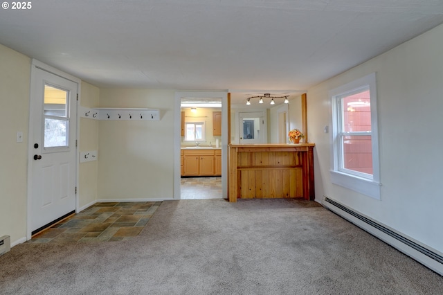 interior space featuring a sink, baseboards, a baseboard heating unit, and carpet flooring