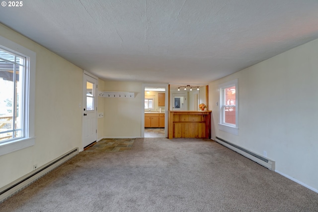 unfurnished living room with a healthy amount of sunlight, a baseboard heating unit, and light colored carpet