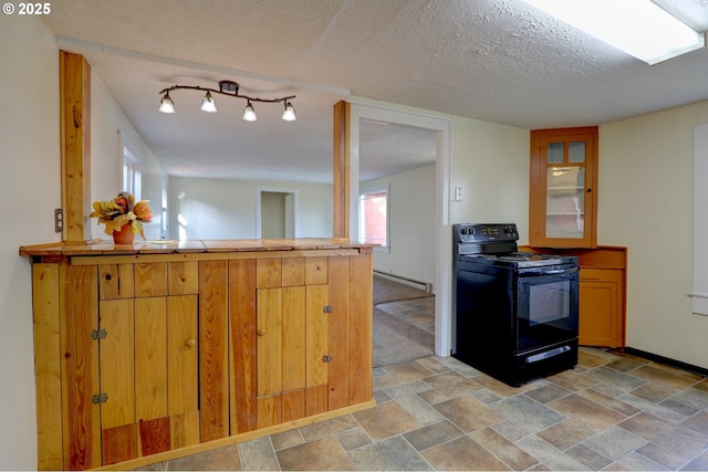 kitchen featuring a baseboard radiator, stone finish flooring, a textured ceiling, a peninsula, and black / electric stove