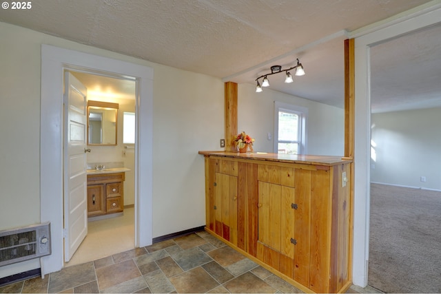 bathroom with baseboards, stone finish floor, heating unit, a textured ceiling, and vanity