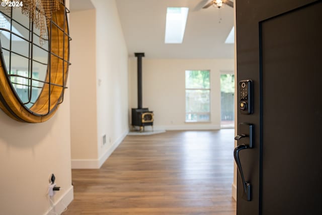 entrance foyer featuring a skylight, a wood stove, hardwood / wood-style flooring, and ceiling fan