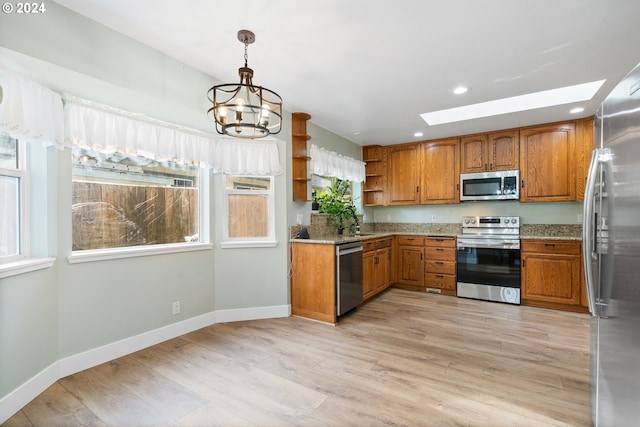 kitchen with light stone countertops, stainless steel appliances, light hardwood / wood-style flooring, a chandelier, and pendant lighting