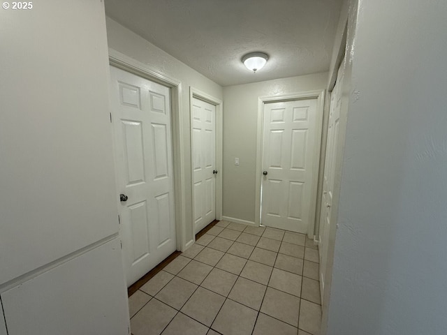 corridor featuring light tile patterned floors and a textured ceiling