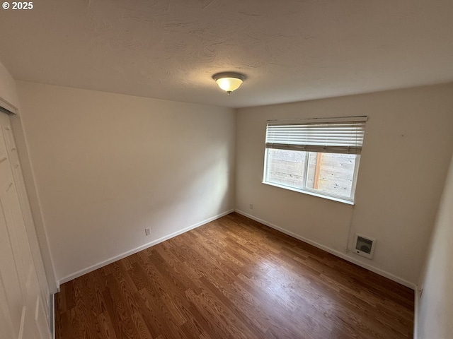 empty room with a textured ceiling and dark hardwood / wood-style floors