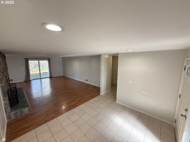 spare room featuring light wood-type flooring and a fireplace